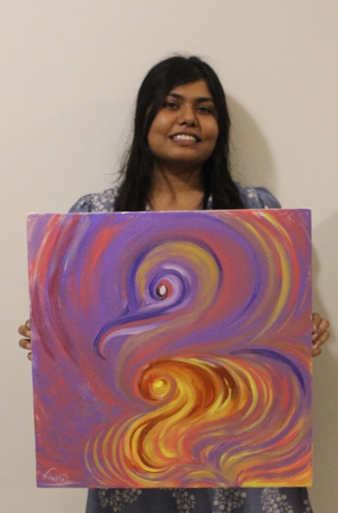 Vishakha holding one of her abstract canvases in violet and gold