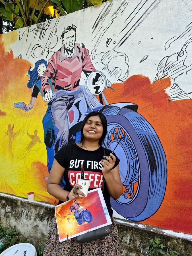 Vishakha smiling in front of a mural she painted