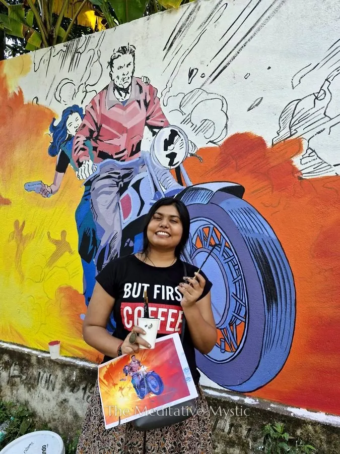 Vishakha smiling in front of a mural she painted