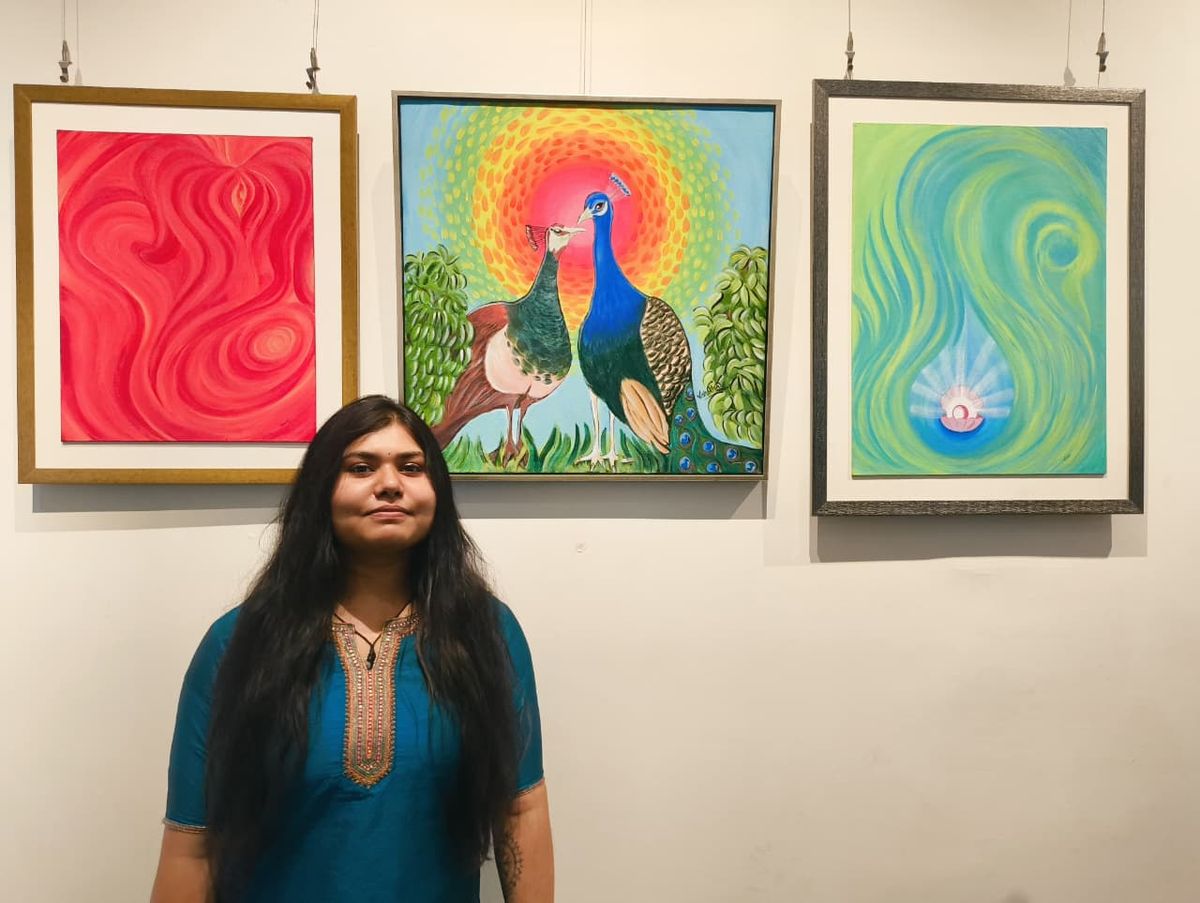 Vishakha with three of her framed paintings at a gallery exhibition