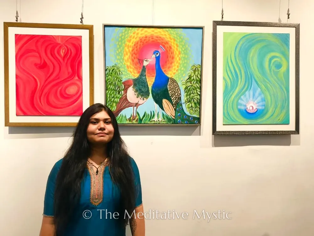 Vishakha with three of her framed paintings at a gallery exhibition