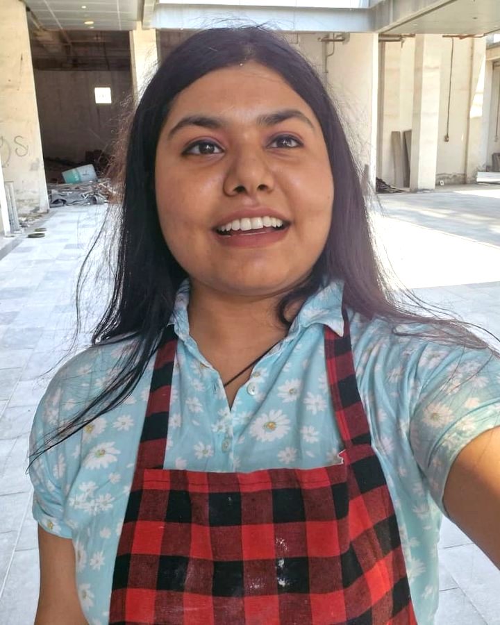 Vishakha in her painting apron, smiling
