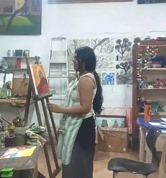Vishakha painting a canvas at an easel in a studio