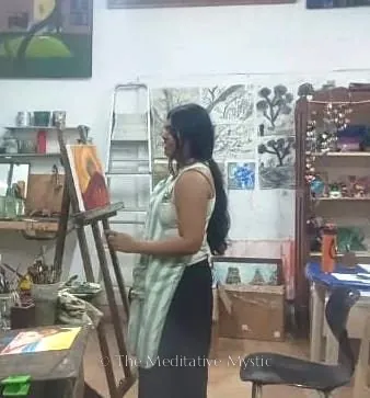 Vishakha painting a canvas at an easel in a studio